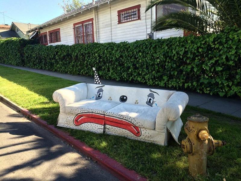 Художник  рисует рожицы грустных клоунов на выброшенных креслах и диванах