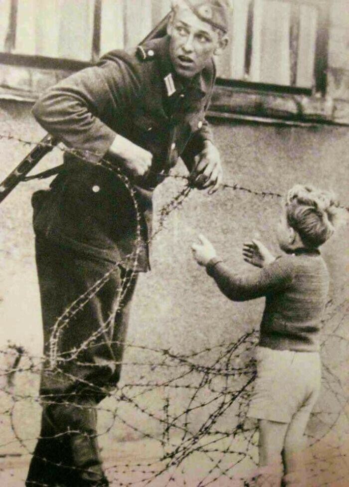 Немецкий солдат ослушался прямого приказа и помогает мальчику, которого разлучили с семьей, пересечь недавно возведенную Берлинскую стену. 1961 год