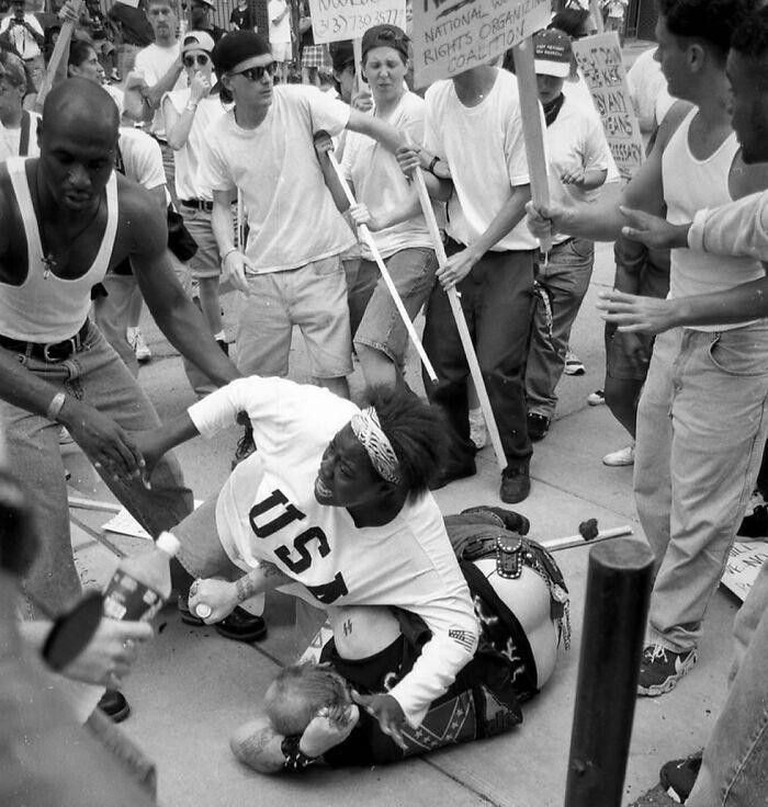 18-летняя Кешия Томас защищает от разъяренной толпы протестующих упавшего мужчину, которого подозревали в связи с Ку-клукс-кланом. Анн-Арбор, Мичиган, США, 1996 год