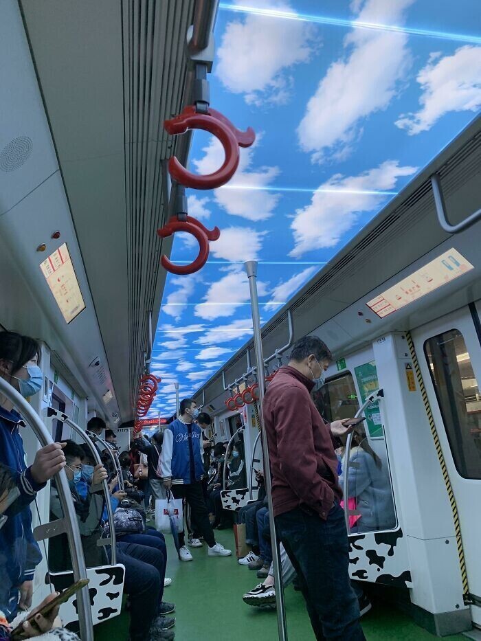 На потолке вагона в поезде метро нарисованы небо и облака