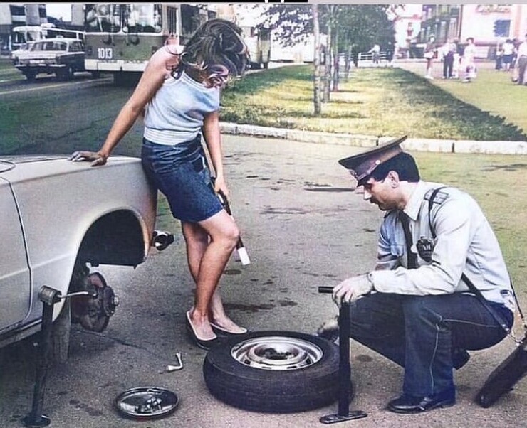 Сотрудник ГАИ помогает девушке заменить колесо. 1981 год