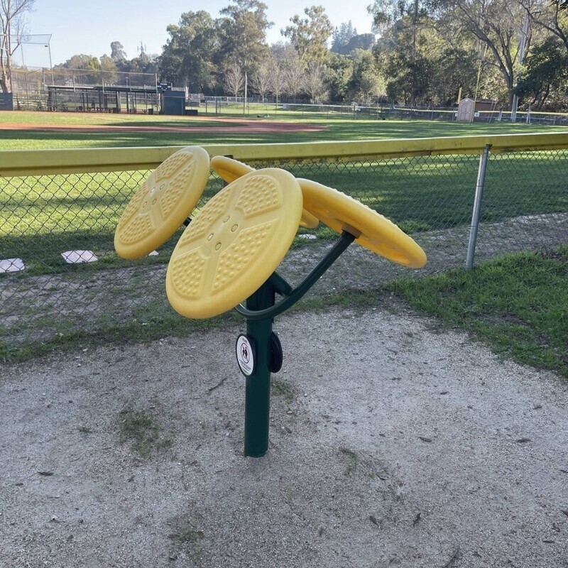 Желтые пластиковые диски, установленные на металлической подставке, замечены возле бейсбольного поля