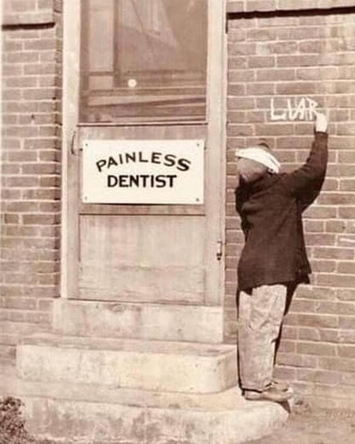 Разочарованный юный пациент пишет «Обманщик» рядом с табличкой «Стоматолог без боли», 1920-й год
