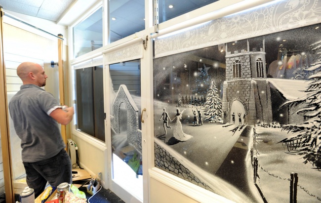 Художник рисует снегом на окнах детской больницы